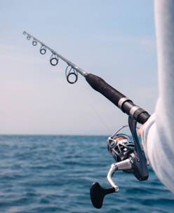 A black and silver fly fishing rod in a person’s hand