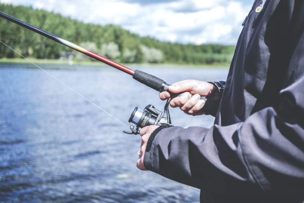 A man holding a fishing rod and reeling in.